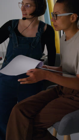 Vertical-Video-Of-Female-Film-Director-And-Assistant-Watching-Actors-And-Checking-Script-Shooting-Movie-Or-Video-Scene-In-Studio